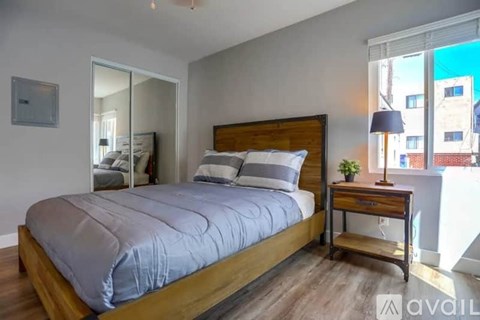 A bedroom with a large bed and a wooden nightstand.