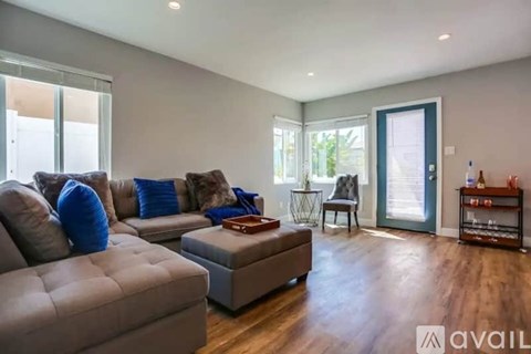 A living room with a grey couch and a brown ottoman.
