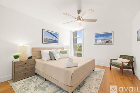 A bedroom with a bed, chair, and two pictures on the wall.
