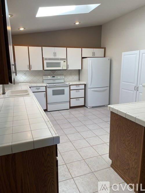 A kitchen with white appliances and wooden cabinets.