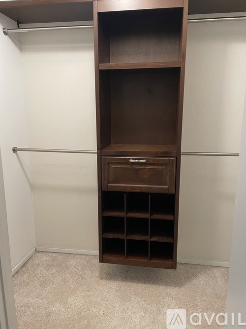 A wooden shelf with a drawer is in a corner of a room.
