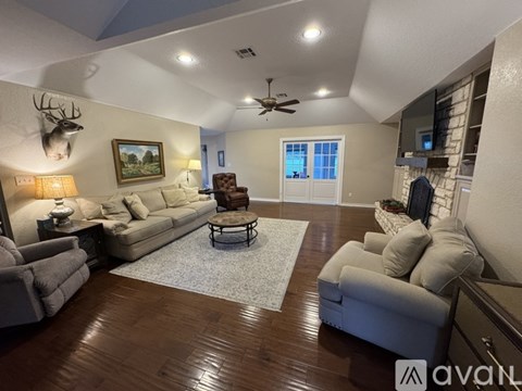 A living room with a white couch, a rug, and a painting of a deer head on the wall.