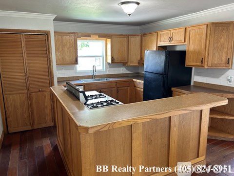 A kitchen with wooden cabinets and a black refrigerator.