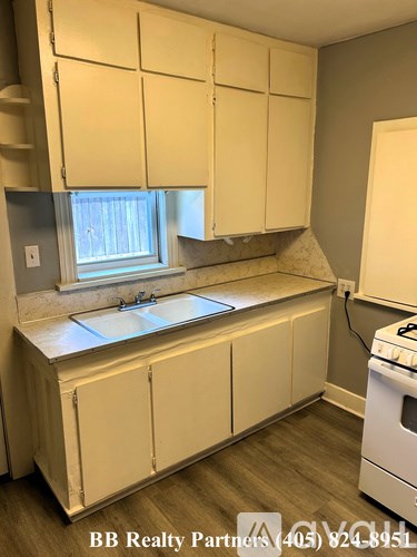 A kitchen with white cabinets and a white stove.