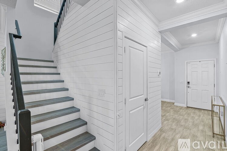 A staircase with a black railing leads up to a white door.