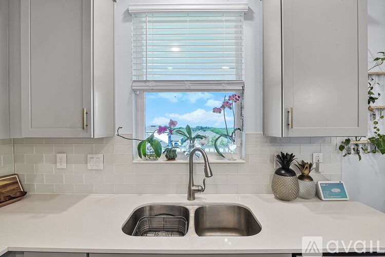 A kitchen with a sink and a window with a view of a garden.