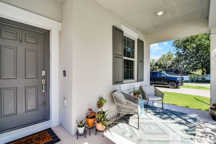 A grey door is on the left of a patio with a table and chairs.