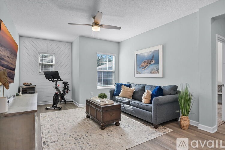 A living room with a grey couch, a rug, a potted plant, and a bicycle.