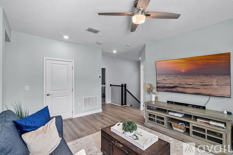 A living room with a couch, a coffee table, a TV, and a painting on the wall.