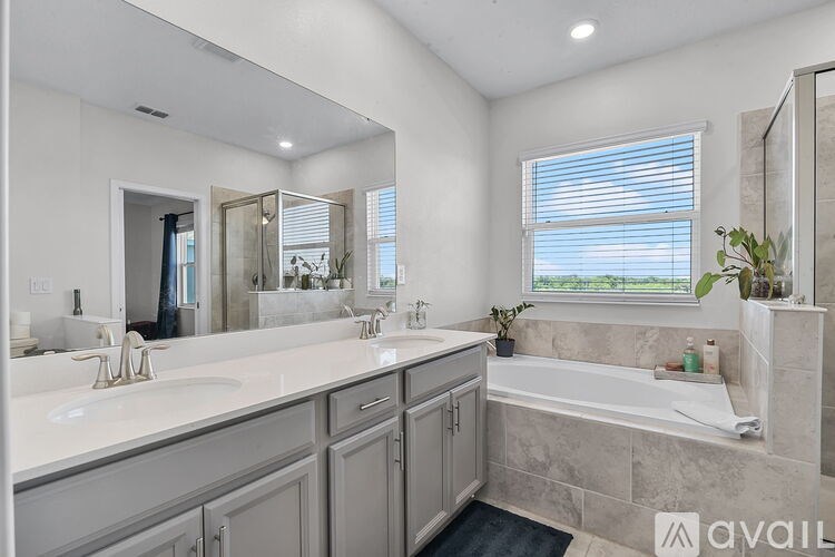 A bathroom with a large mirror, double sinks, and a bathtub.
