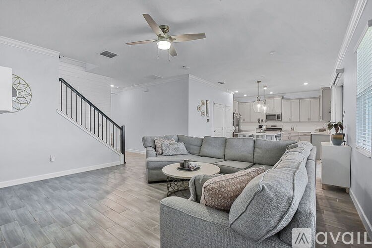 A living room with a grey couch and a fan on the ceiling.