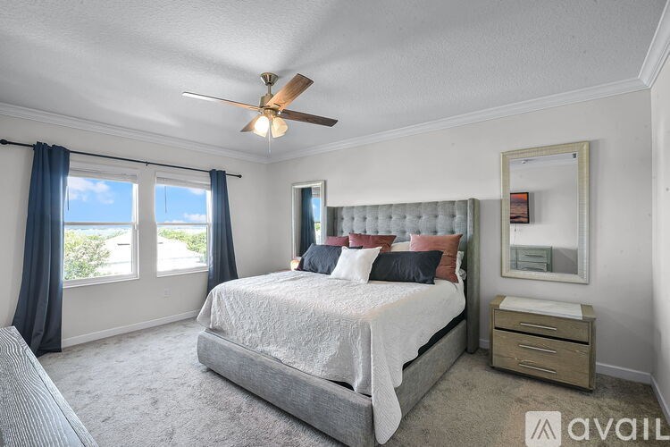 A bedroom with a large bed, a ceiling fan, and a window with a view of the ocean.