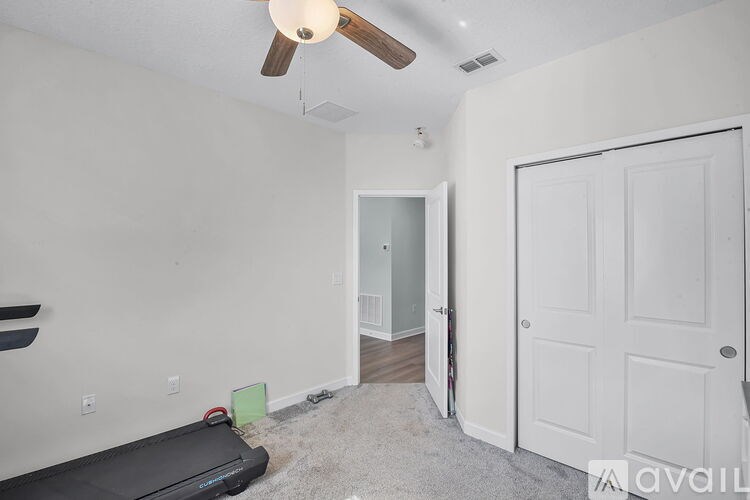 A room with a ceiling fan and a door leading to another room.