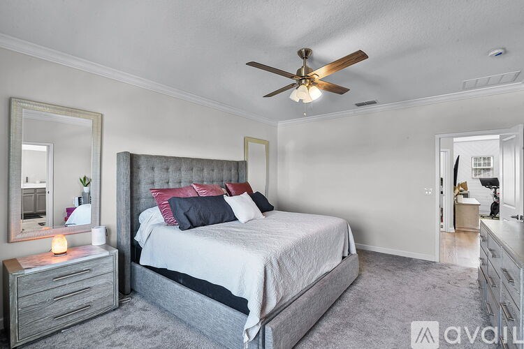 A bedroom with a bed, dresser, mirror, and a ceiling fan.