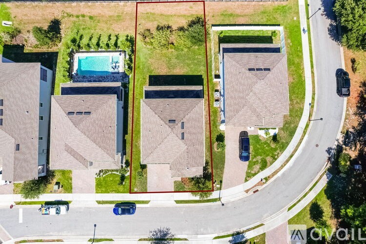 A bird's eye view of a residential area with houses, a pool, and a street.