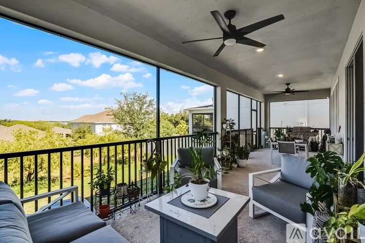A balcony with a table, chairs, and plants.