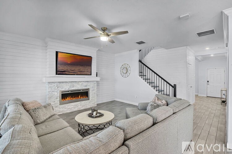 A living room with a grey couch, a fireplace, and a painting on the wall.