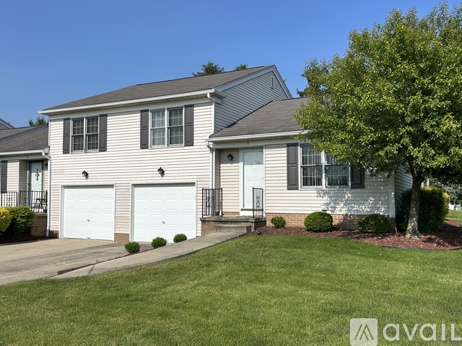 A two-story house with a garage and a tree in front.
