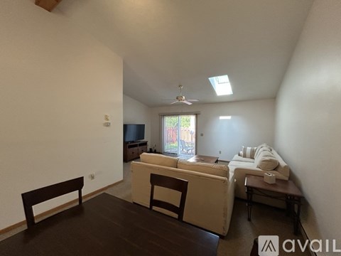 A living room with a brown table and white couches.