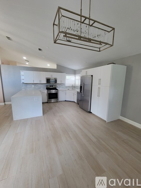 A kitchen with white cabinets and a wooden floor.