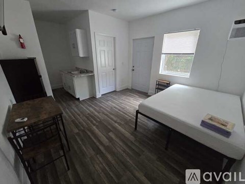 A bedroom with a bed, a table, and a cabinet.