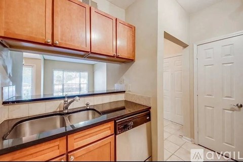 A kitchen with wooden cabinets and a stainless steel sink.