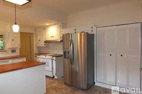 A kitchen with a stainless steel refrigerator and white cabinets.