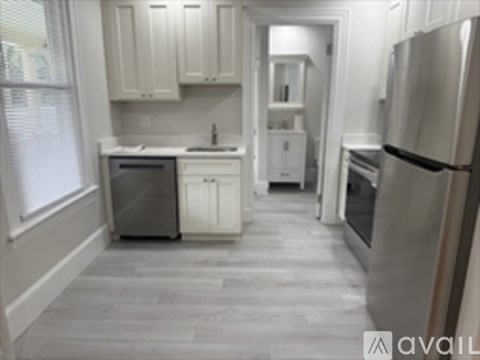 A kitchen with white cabinets and a refrigerator.