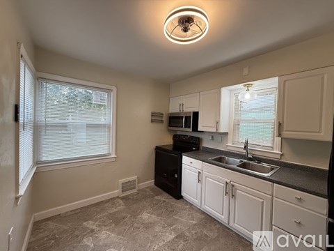 A kitchen with a black dishwasher and white cabinets.
