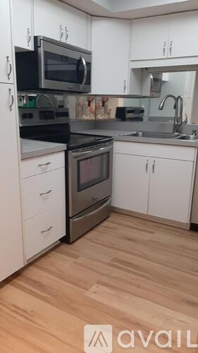 A kitchen with white cabinets and wooden floors.
