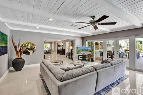 A spacious living room with a grey sofa and a ceiling fan.