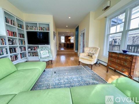 A living room with a green sofa and a bookshelf filled with books.