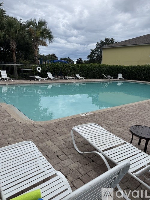 A pool with sun loungers and a table.