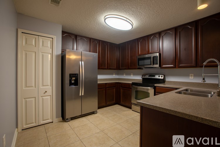 A kitchen with brown cabinets and a stainless steel refrigerator.
