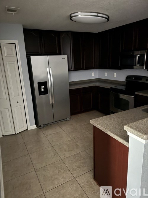 A kitchen with a refrigerator, microwave, and oven.