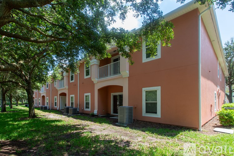 A row of pink houses with trees in front.