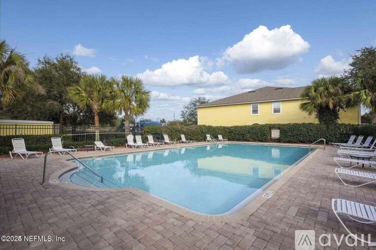 A pool surrounded by lounge chairs and palm trees.