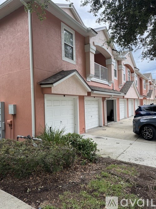 A row of pink houses with a car parked in front of the first one.