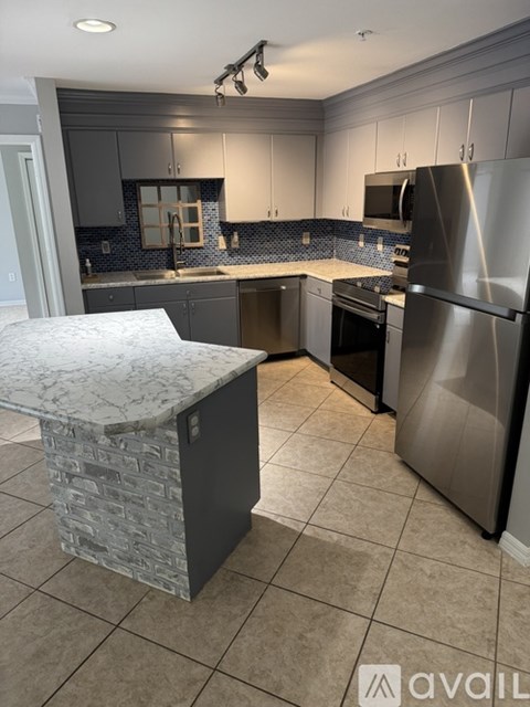 A kitchen with a marble island and stainless steel appliances.