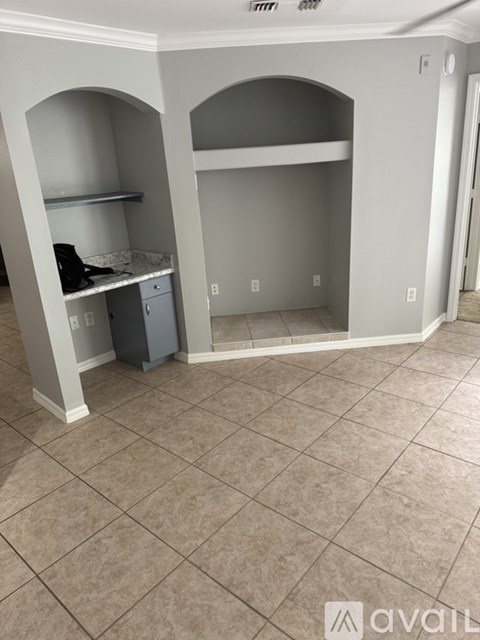 A room with a tile floor and a cabinet under an arch.