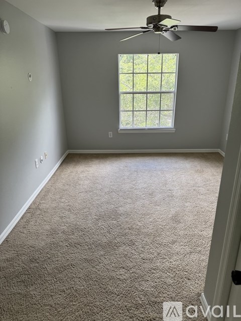A room with a carpeted floor and a ceiling fan.