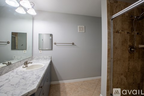 A bathroom with a marble sink and a shower with a glass door.