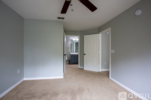 A room with a carpeted floor and a ceiling fan.