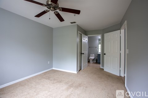 A room with a ceiling fan and carpeted floor.