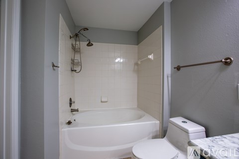 A white bathroom with a tub, toilet and sink.