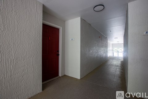 A hallway with a red door and a sign on the wall.