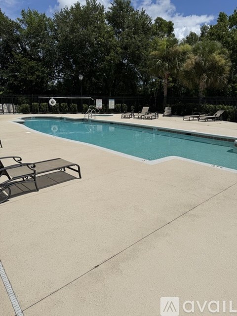 A pool with a diving board and lounge chairs.