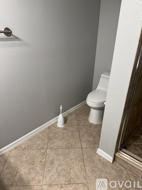 A white toilet sits in a bathroom next to a white wall.