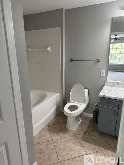 A white toilet in a bathroom with a white tub and a white towel rack.