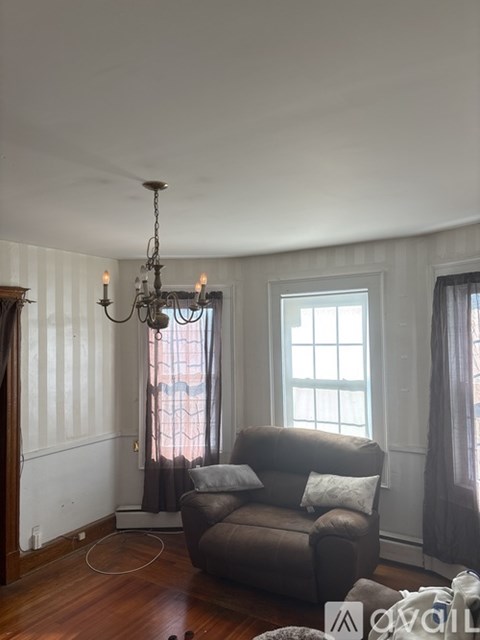 A living room with a grey couch and a chandelier.